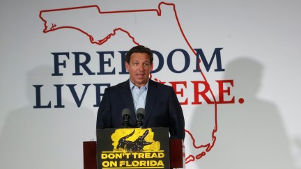 Ron DeSantis speaks from a podium with a banner behind him reading 