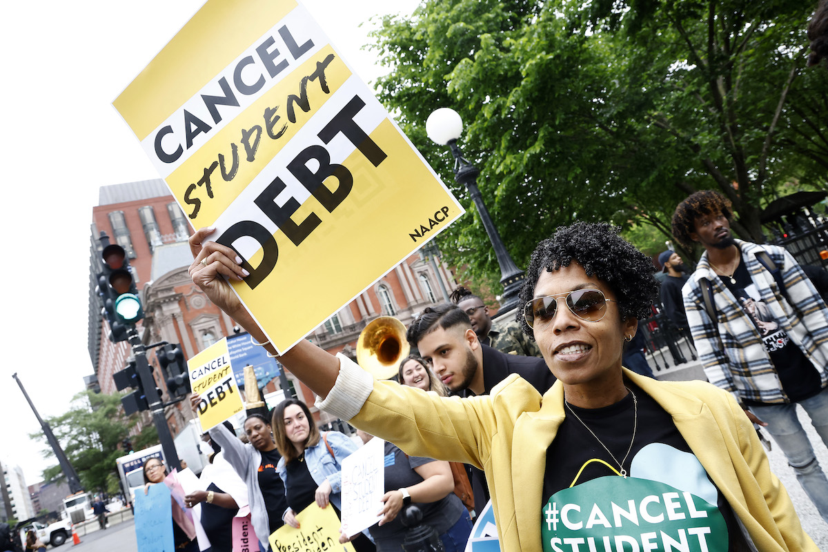 At a protest, one demonstrator holds a sign reading "cancel student debt"