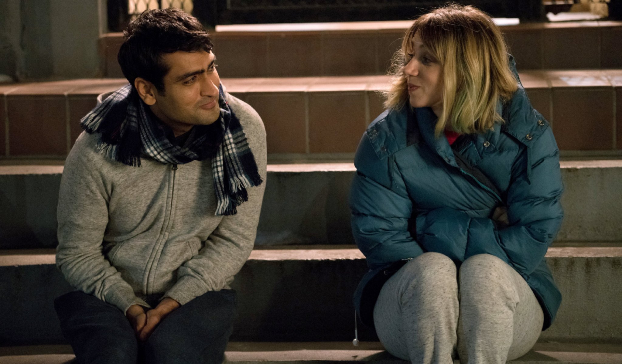 Kumail Nanjiana and Zoe Kazan from the movie, The Big Sick, sit on stairs outside together.