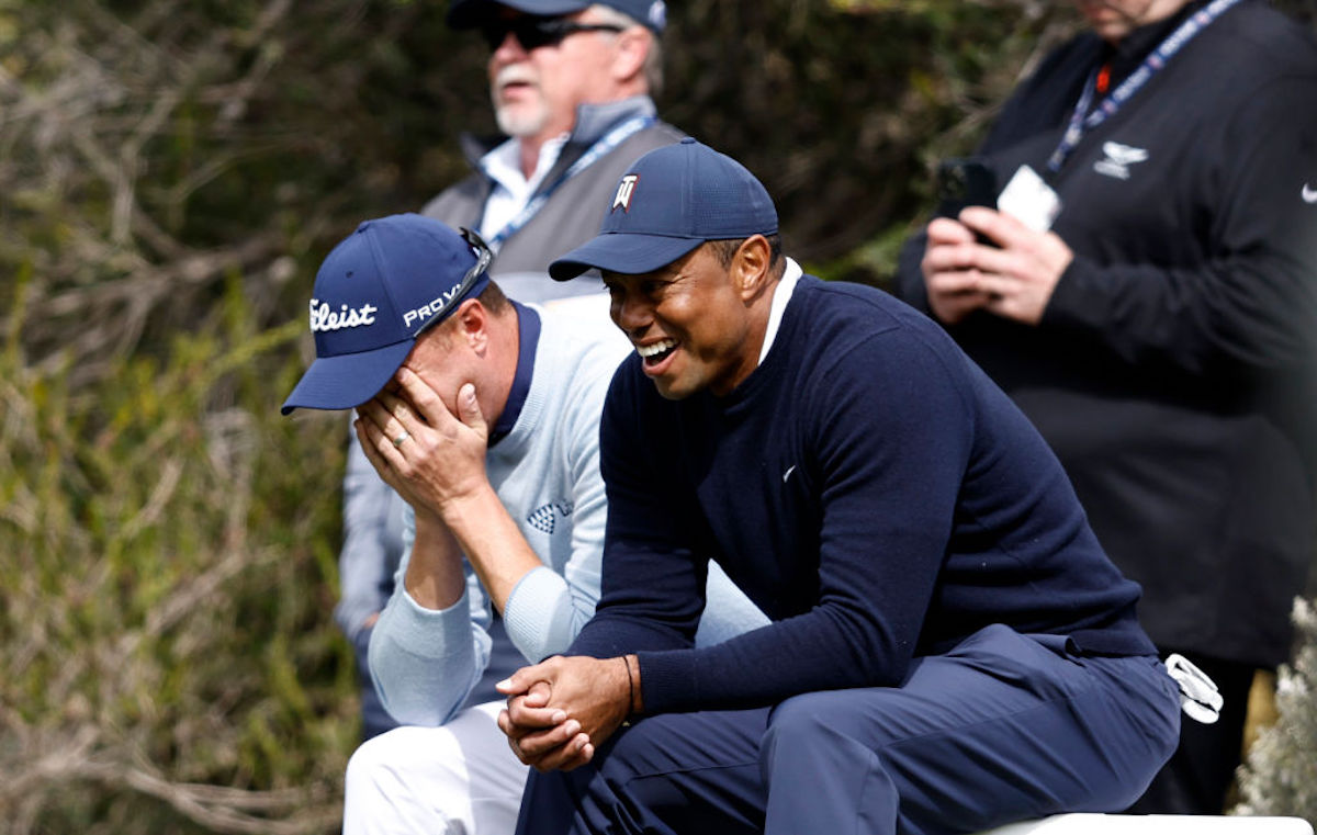 Tiger Woods and a white male golfer sit and laugh together.
