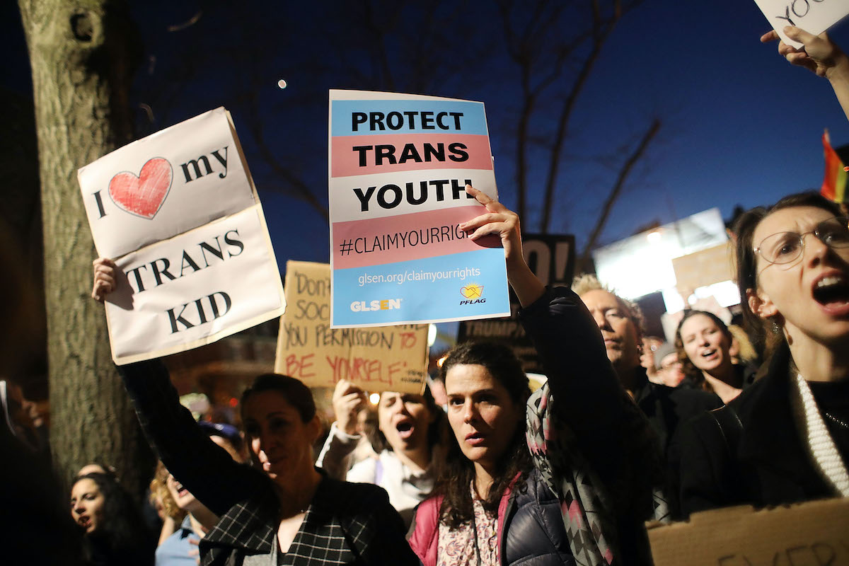 A group of protesters holding signs reading "protect trans youth" and "I Heart My Trans Kid"