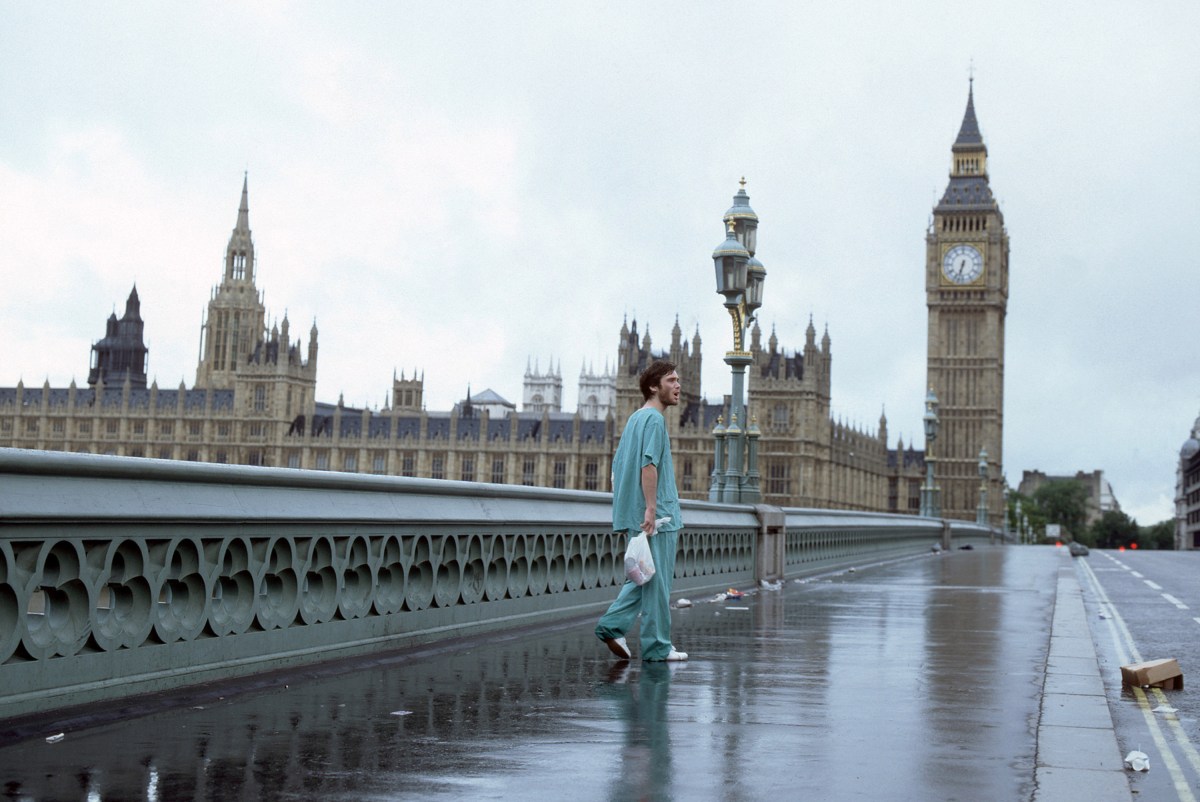 A white man in hospital scrubs stands alone on London's Westminster Bridge in "28 Days Later"