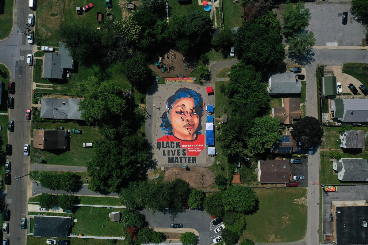 In an aerial view from a drone, a large-scale ground mural depicting Breonna Taylor with the text 'Black Lives Matter' is seen.