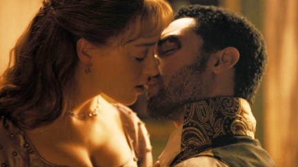 A white woman and a biracial Black man kiss sensually in Regency era dress.