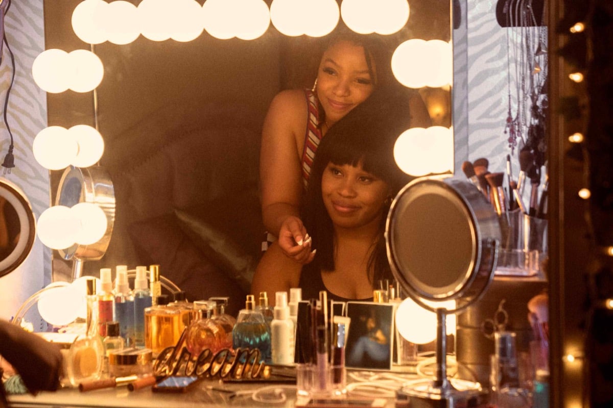 Marissa (Chloe Bailey) and Dre (Dominique Fishback) are reflected in a vanity mirror