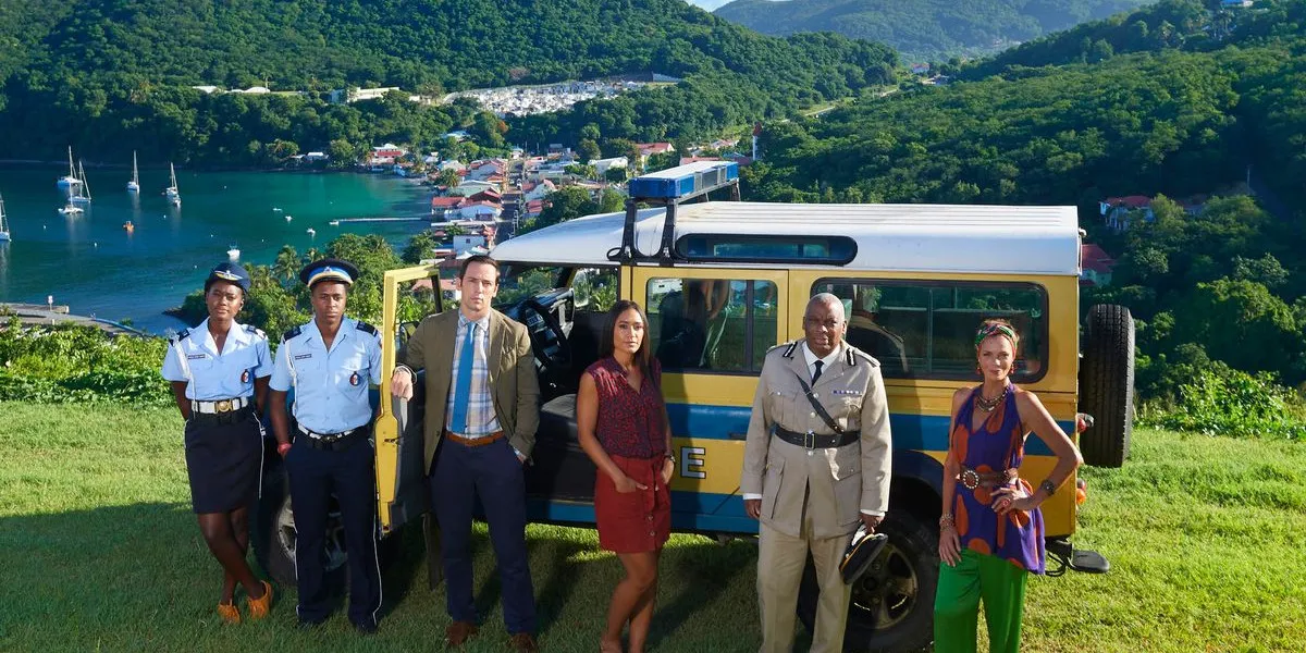 The cast of Death in Paradise with a beautiful island backdrop 