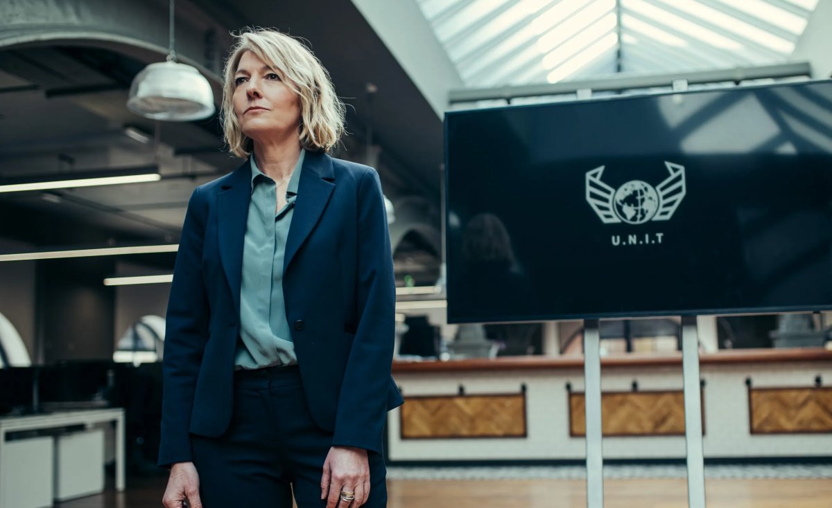 Kate Stewart, played by Jemma Redgrave, standing in front of a screen that reads UNIT