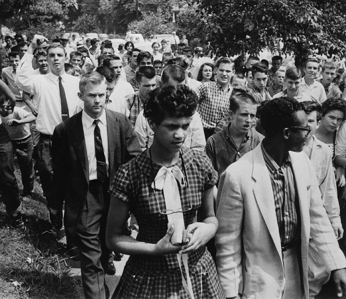 Dorothy Geraldine Counts, 15 (left) is followed by a crowd of jeering teenagers as she leaves Harding high school with her escort, Dr R.A. Hawkins, 4th September 1957