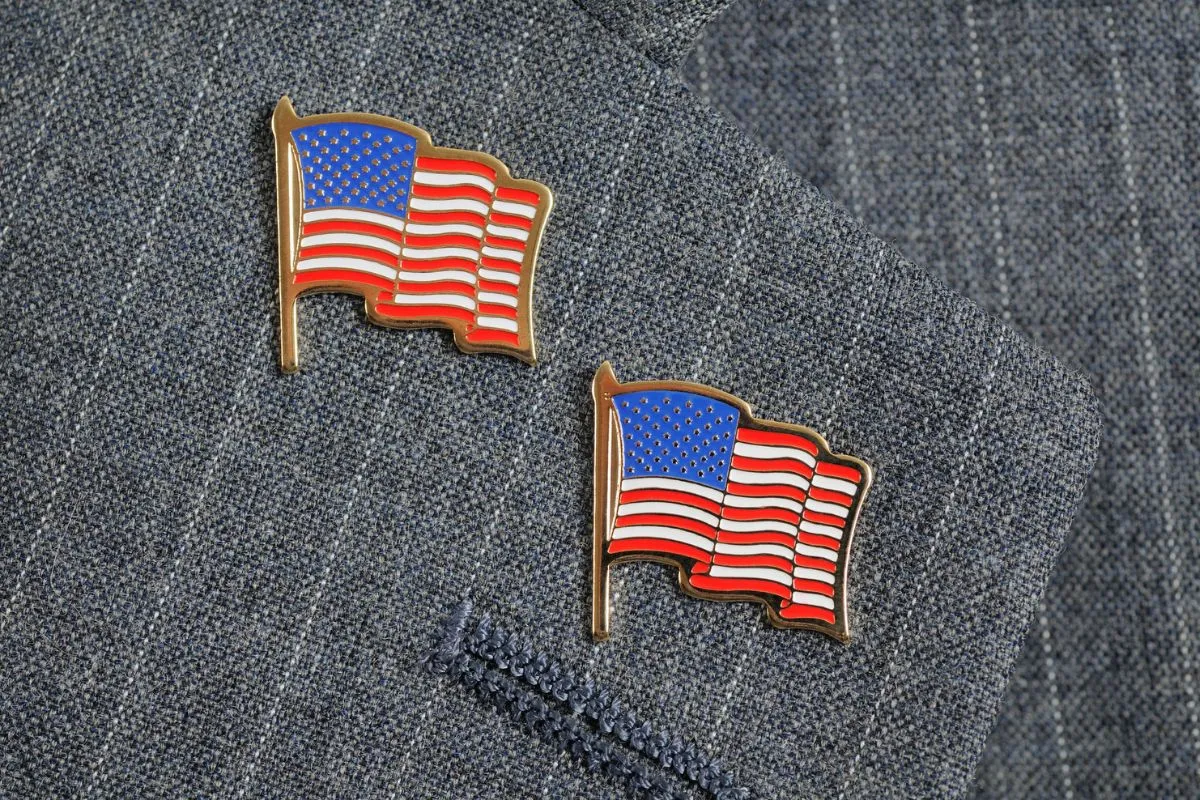 A pair of American flag pins on a pinstripe suit lapel.