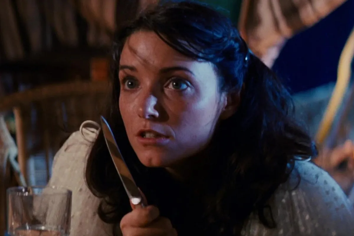 Young Marion (Karen Allen) peers at the viewer wide eyed while holding a knife