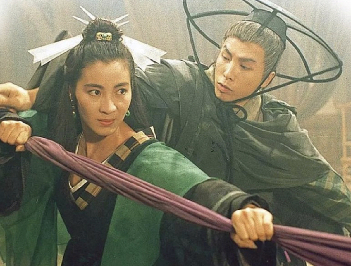 Michelle Yeoh in a martial arts stance with Donnie Yen standing behind her, both wearing traditional Chinese costumes, in the film Butterfly and Sword