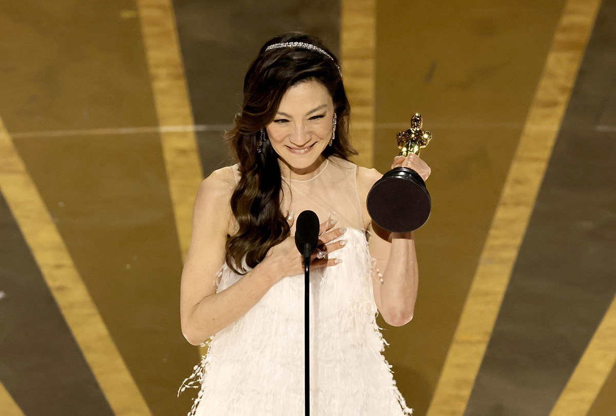Michelle Yeoh holding up her Oscars