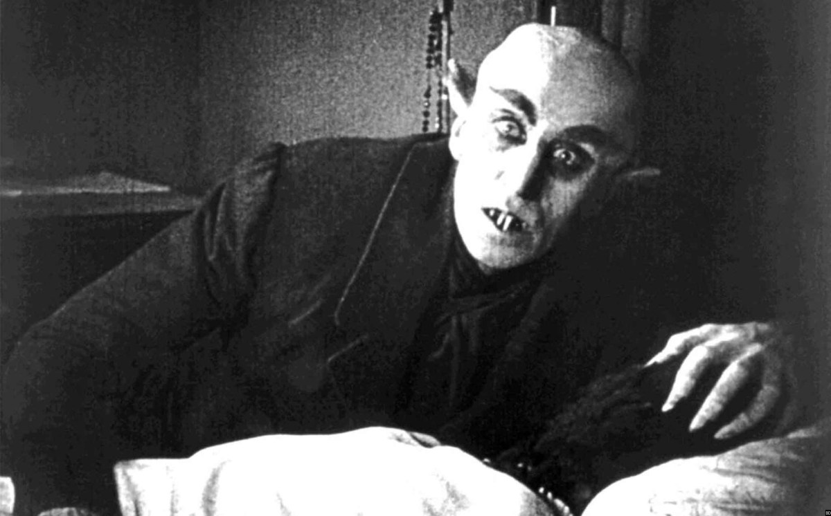 A vampire rises from his bed with a curious look on his face in the movie "Nosferatu"
