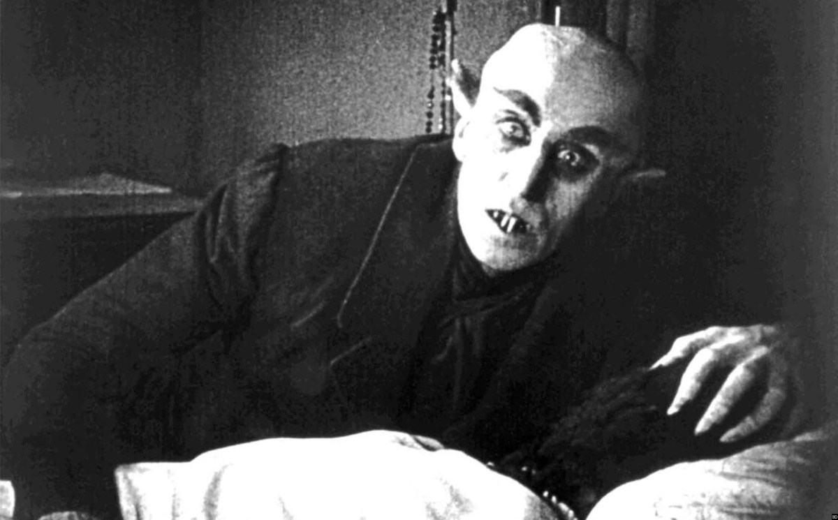 A vampire rises from his bed with a curious look on his face in the movie "Nosferatu"