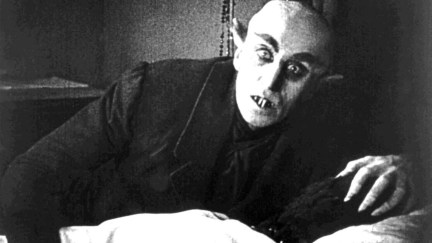 A vampire rises from his bed with a curious look on his face in the movie 