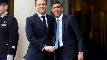 French President Emmanuel Macron welcomes British Prime Minister Rishi Sunak smile widely as they meet to discuss the future of refugee policies