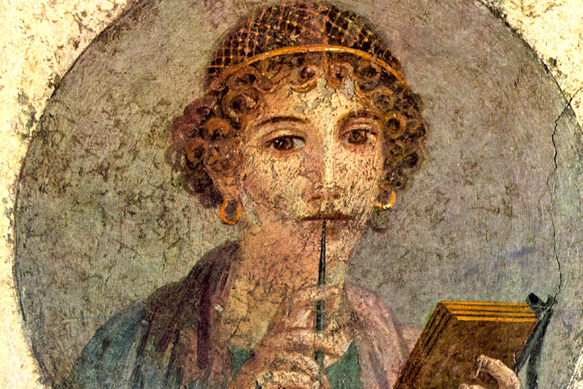 A fresco of a young ancient woman holding a stylus to her lips and a tablet in her other hand.