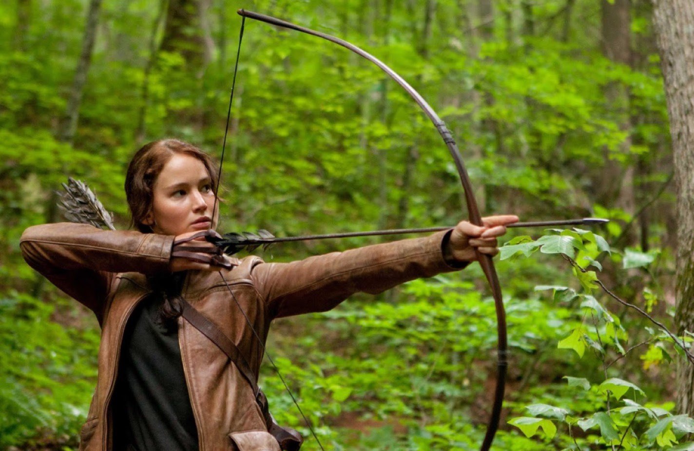 Katniss Everdeen, played by Jennifer Lawrence, hunts in the woods outside of District 12 in the first The Hunger Games movie