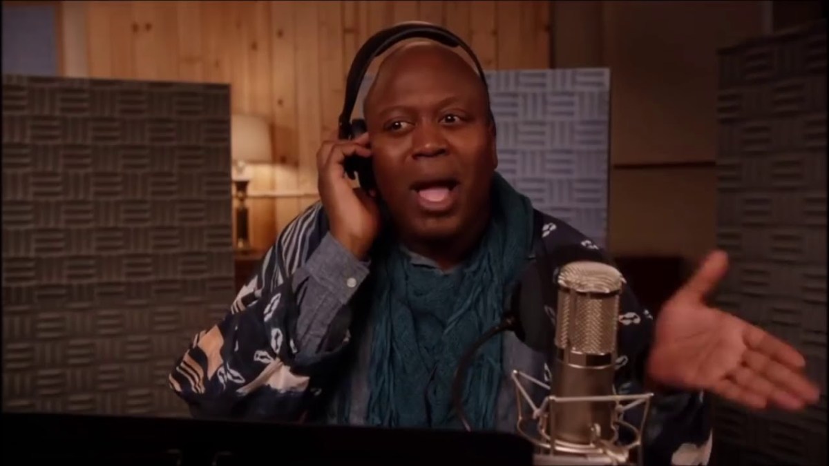 Titus Andromedon wears headphones as he's mid singing