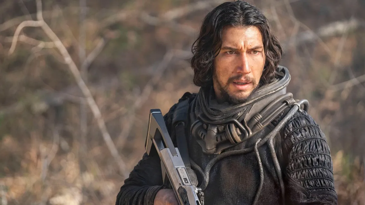 Adam Driver with a gun ready to shoot some dinos in 65