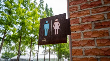 A sign for a bathroom outside a building, showing male and female outlines