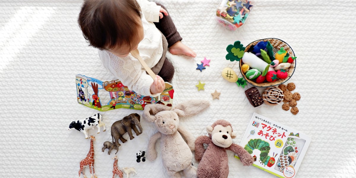 A toddler playing with various toys on a white carpet