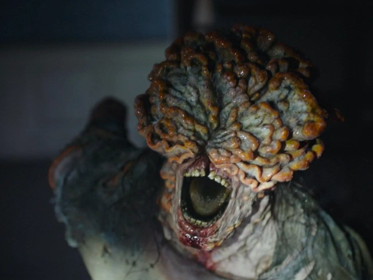 Close up image of an adult clicker charging forward. Its face is entirely obscured by fungal plates. Its mouth is open wide, and blood drips from it.