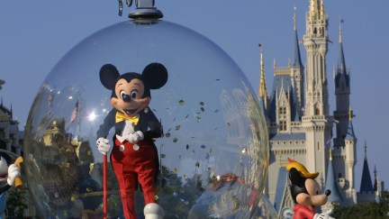 A float carrying Mickey Mouse travels in front of the Disney World castle.