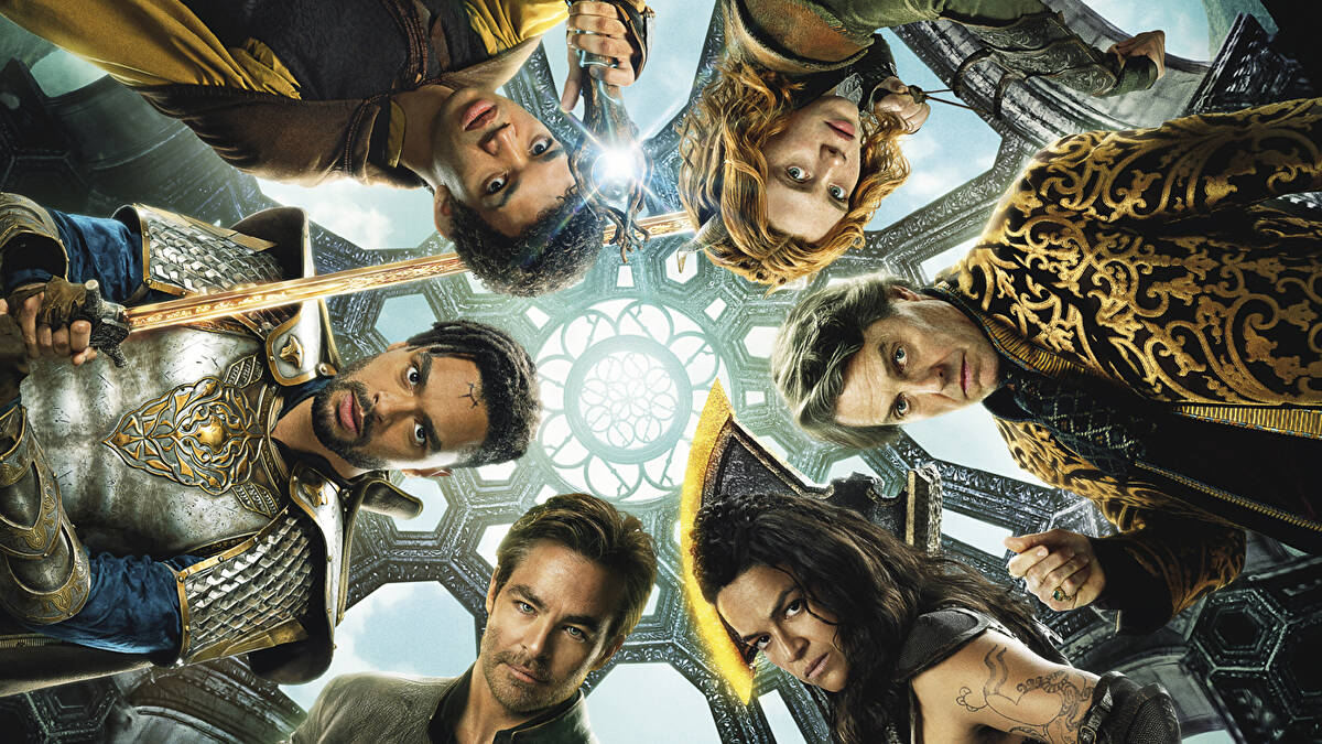 Cropped image from the movie poster for 'Dungeons & Dragons: Honor Among Thieves.' The main characters are standing in a circle looking down at the camera under an ornate roof that lets in sunlight. Starting at the top and going clockwise: Justice Smith as Simon, a young, Black man with short, curly dark hair, wearing a cape and holding a glowing staff. Sophia Lillis as Doric, a young, white woman with red hair holding a slingshot. Hugh Grant as Forge, a white man with short, light brown hair and wearing an ornate, gold and black embroidered coat. Michelle Rodriguez as Holga, a Latina woman with brown skin, long, dark hair, and holding an axe. Chris Pine as Edgin, a white man with short, blond hair and a 5 o'clock shadow beard. And Regé-Jean Page as Xenk, a Black man with short, black hair styled in twists on one side and a beard wearing a suit of silver, gold, and blue armor, and holding up a sword.