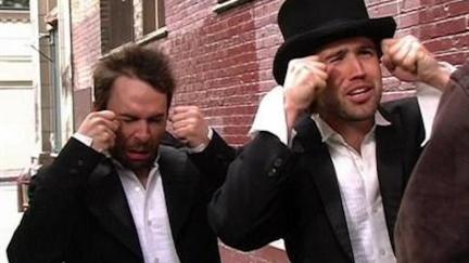 Mac and Charlie from It's Always Sunny in Philadelphia, wearing tuxedos and fake crying.