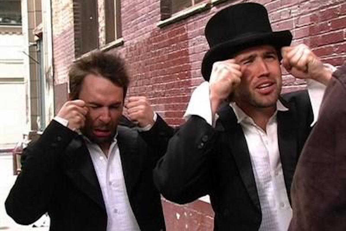 Mac and Charlie from It's Always Sunny in Philadelphia, wearing tuxedos and fake crying.