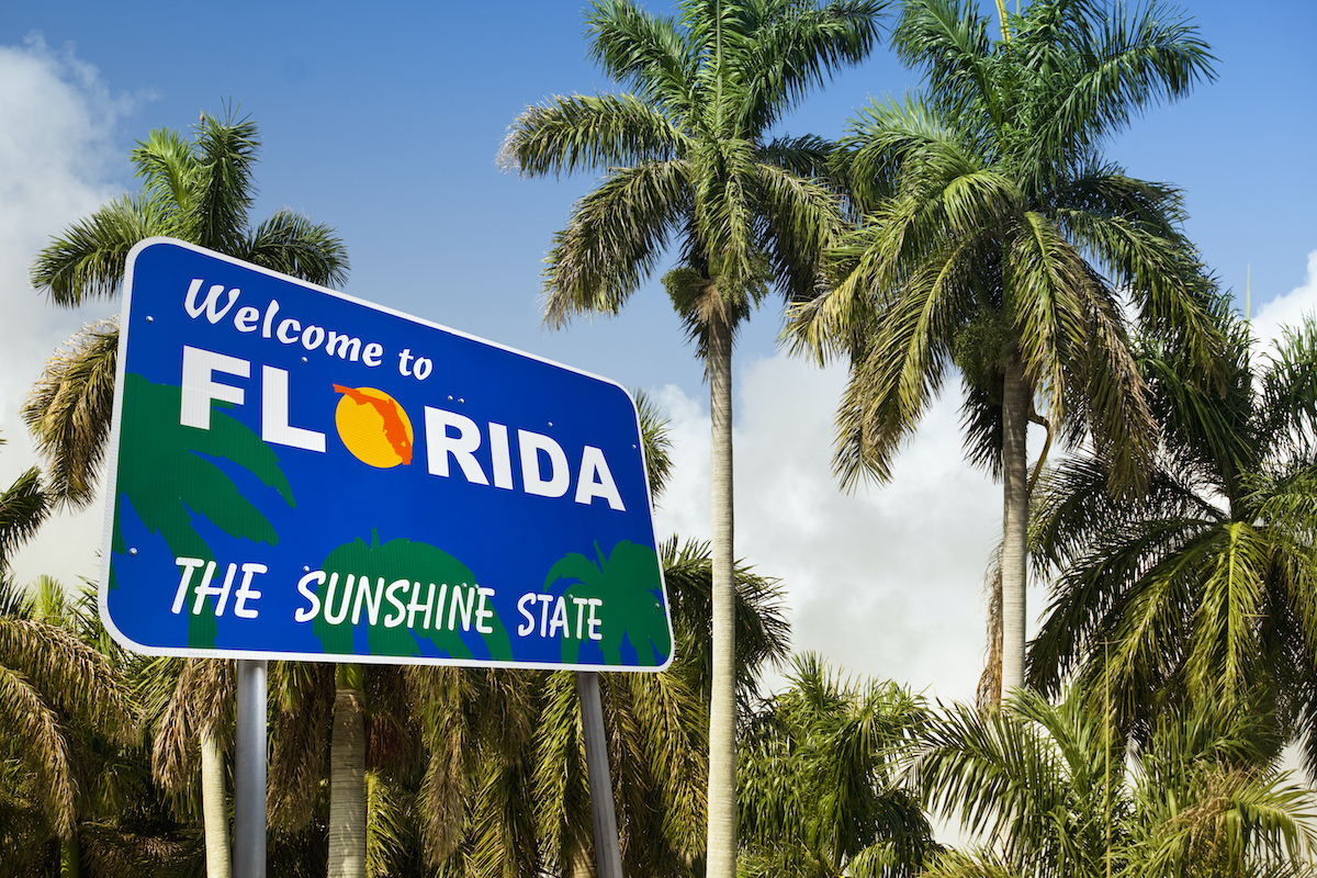 Road sign reading "Welcome to Florida" Palm trees in the background.