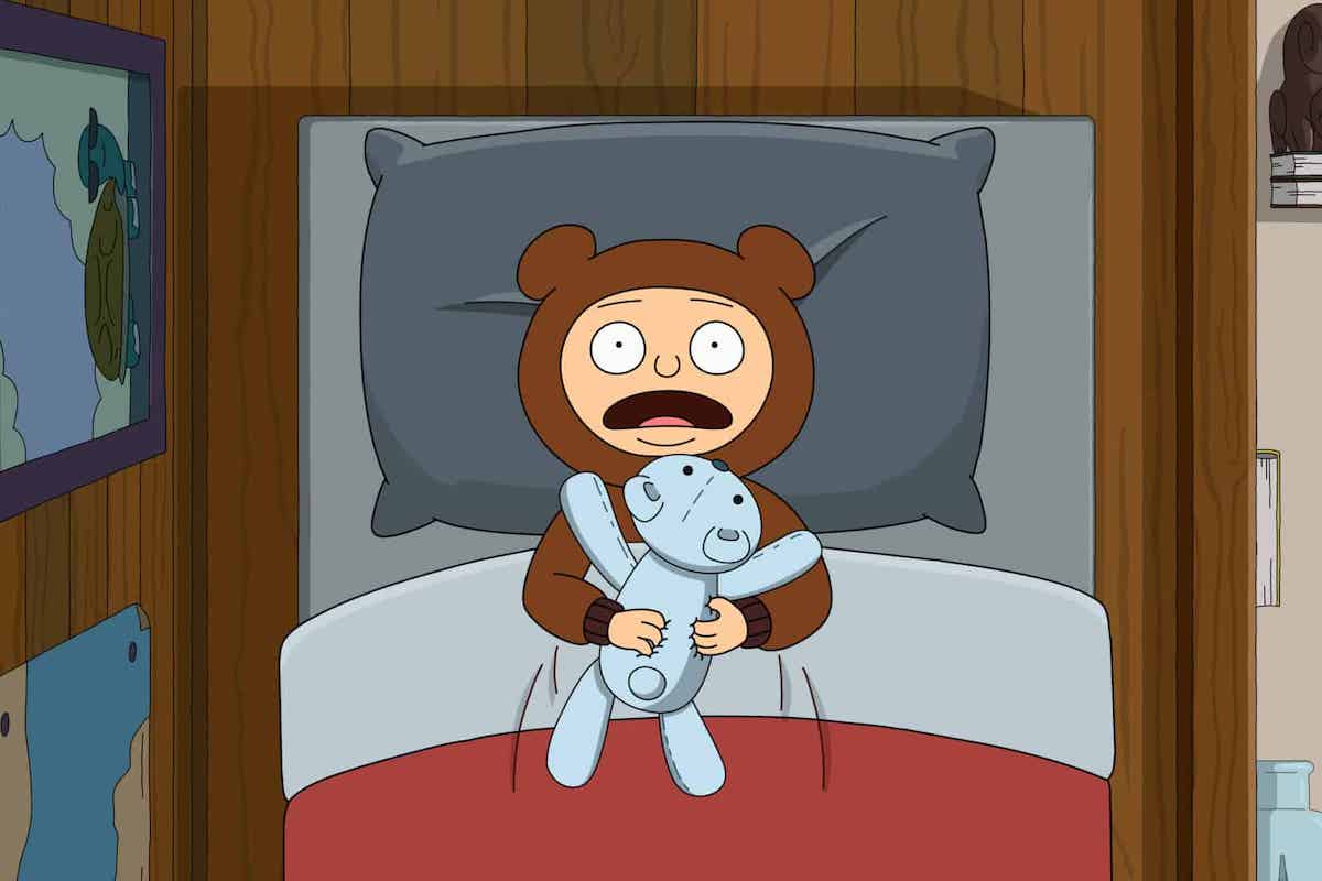 Animated character Moon, a young boy, seen from above in his bed, clutching a stuffed animal, yelling