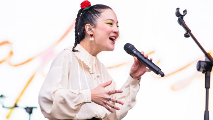 A young Asian woman (Michelle Zauner) speaks or sings into a microphone on a stage