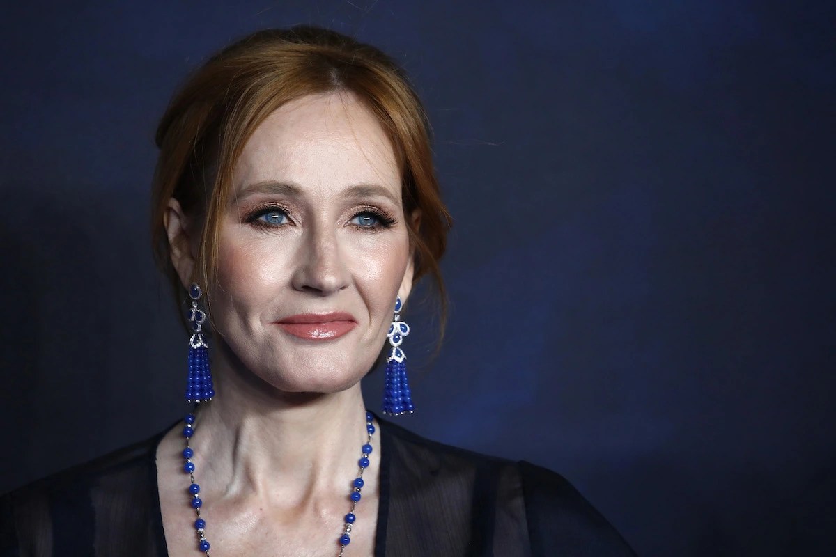 J.K. Rowling smiles against a dark blue background.