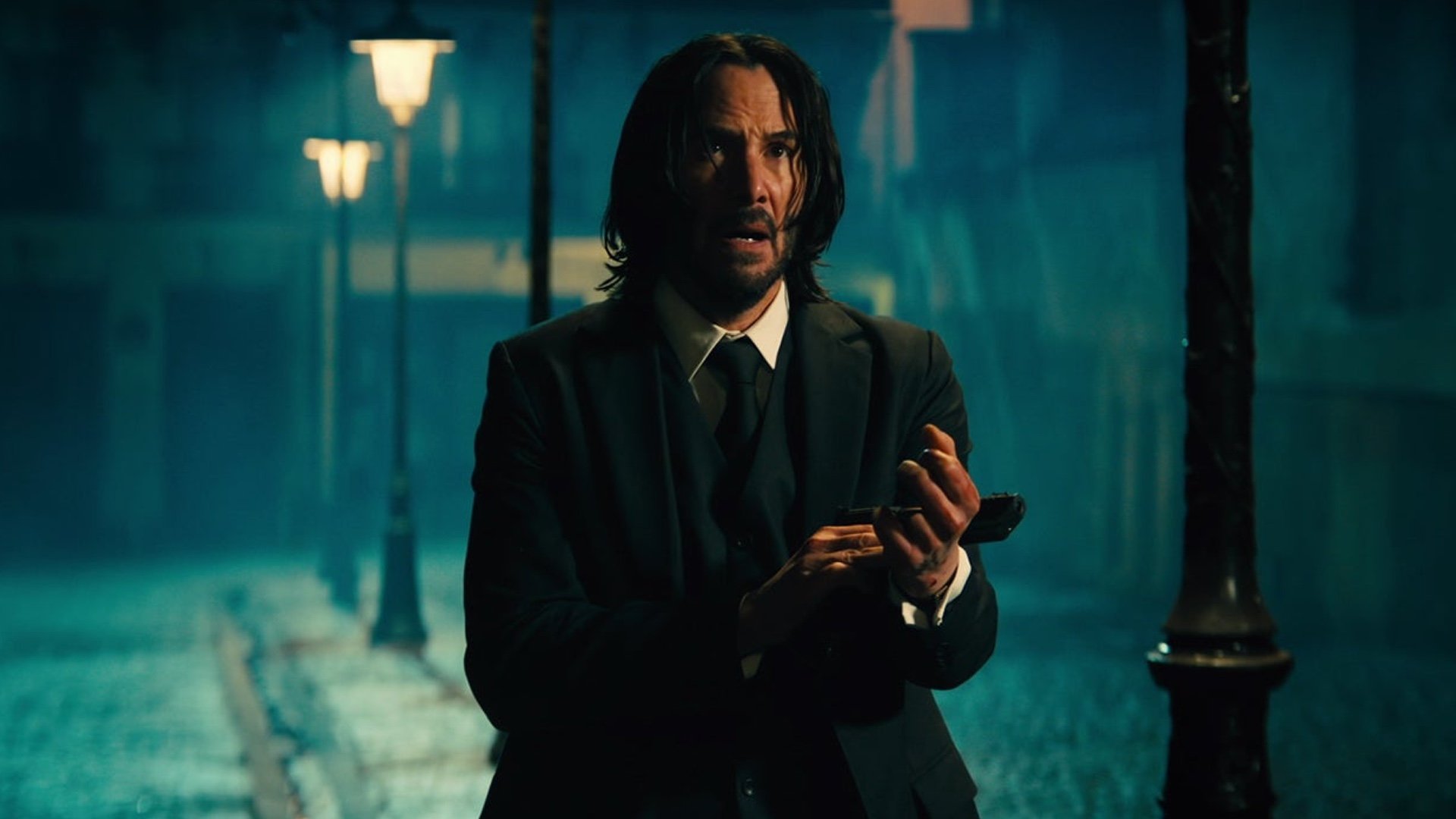 Keanu Reeves as John Wick reloading a gun in John Wick 4