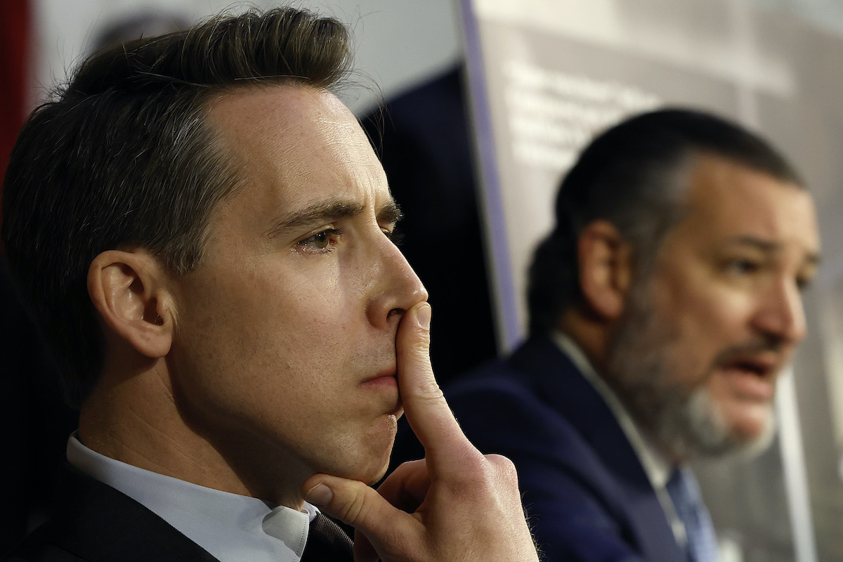 Josh Hawley sits, staring intently, with his index finger pushed up against his nose.
