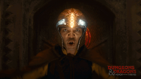 GIF of Justice Smith as Simon in 'Dungeons & Dragons: Honor Among Thieves.' He is a young, Black man wearing a gold, magical helmet from which he's drawing light and shooting out a spell with both hands. 
