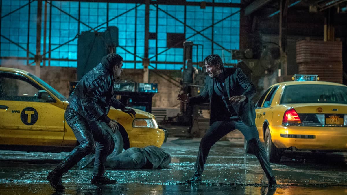 Keanu Reeves in a fight scene on a street in the rain in John Wick Chapter 2.