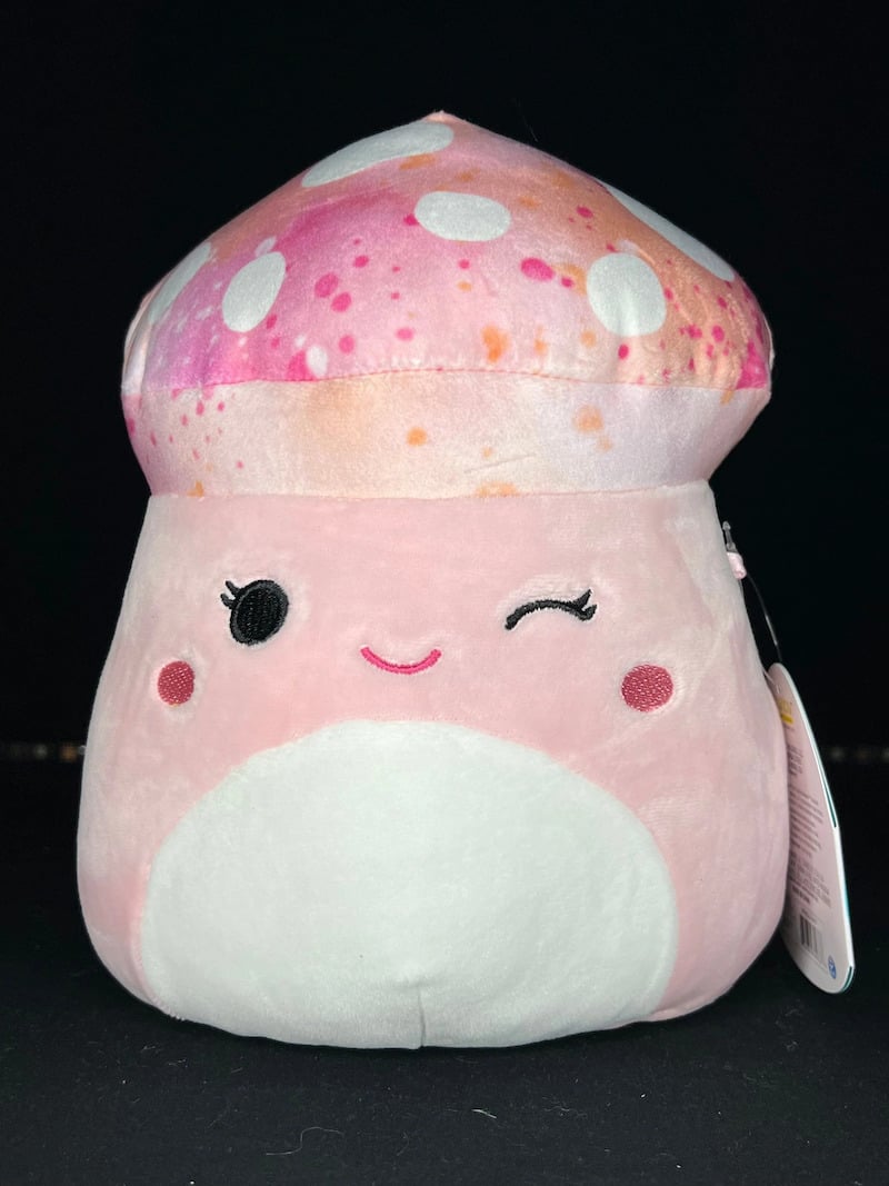 A pink mushroom Squishmallow with a cosmic patterned cap, winking.