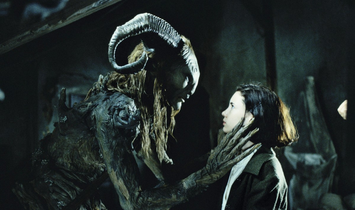 A curved horned creature and a small woman look at each other in "Pans Labyrinth"
