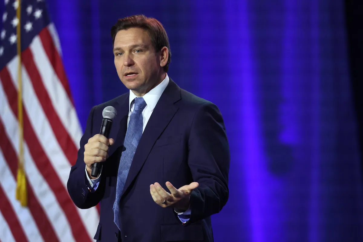 Ron Desantis speaks into a microphone at an event.