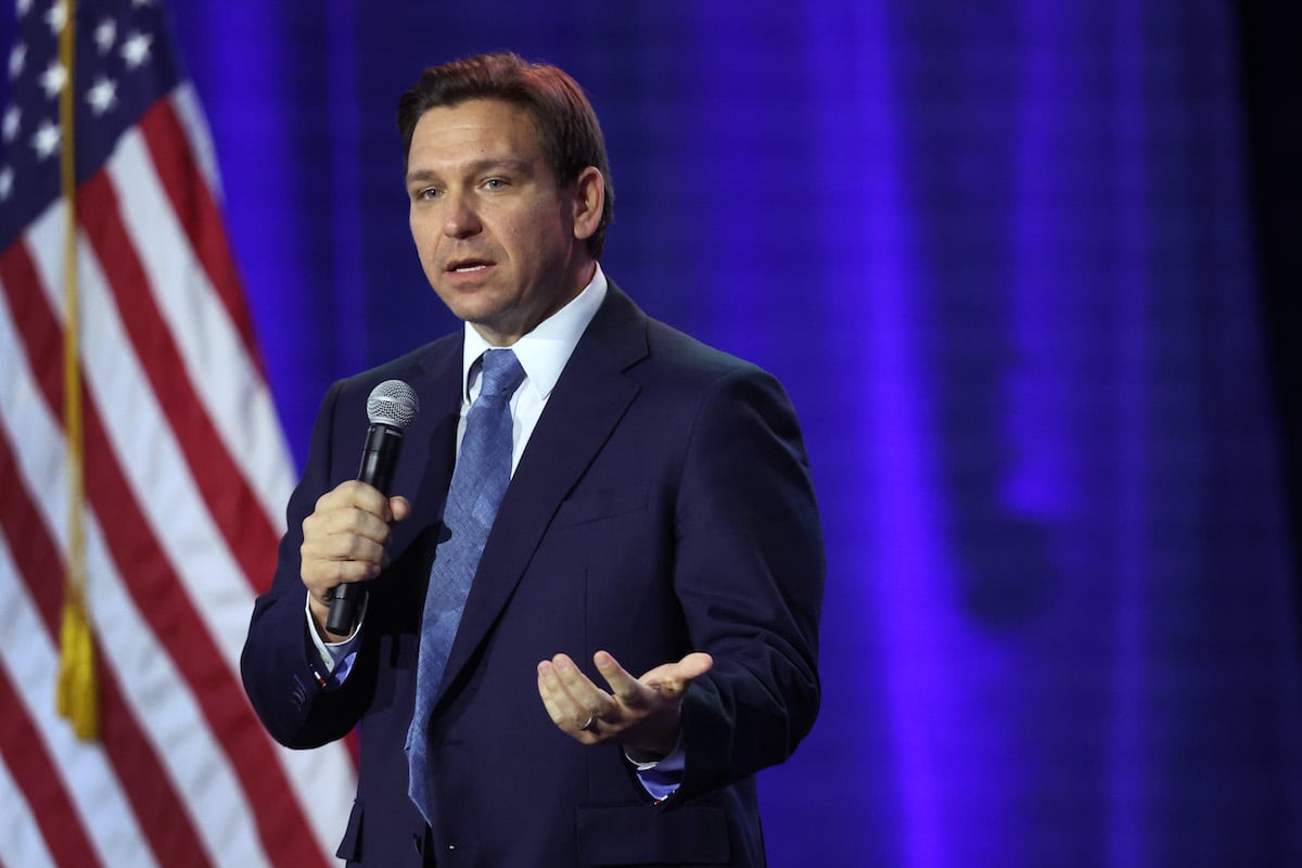 Ron Desantis speaks into a microphone at an event.