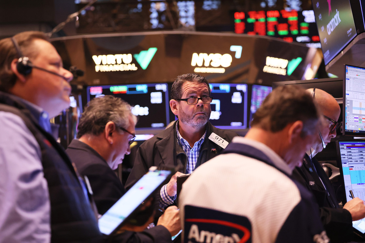A group of white men look worried on the floor of the New York Stock Exchange.