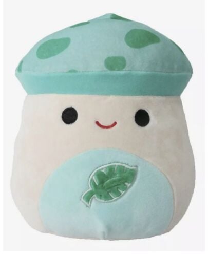 A mushroom squishmallow with a pale blue stomach with an embroidered leaf on it and a blue and green spotted cap.