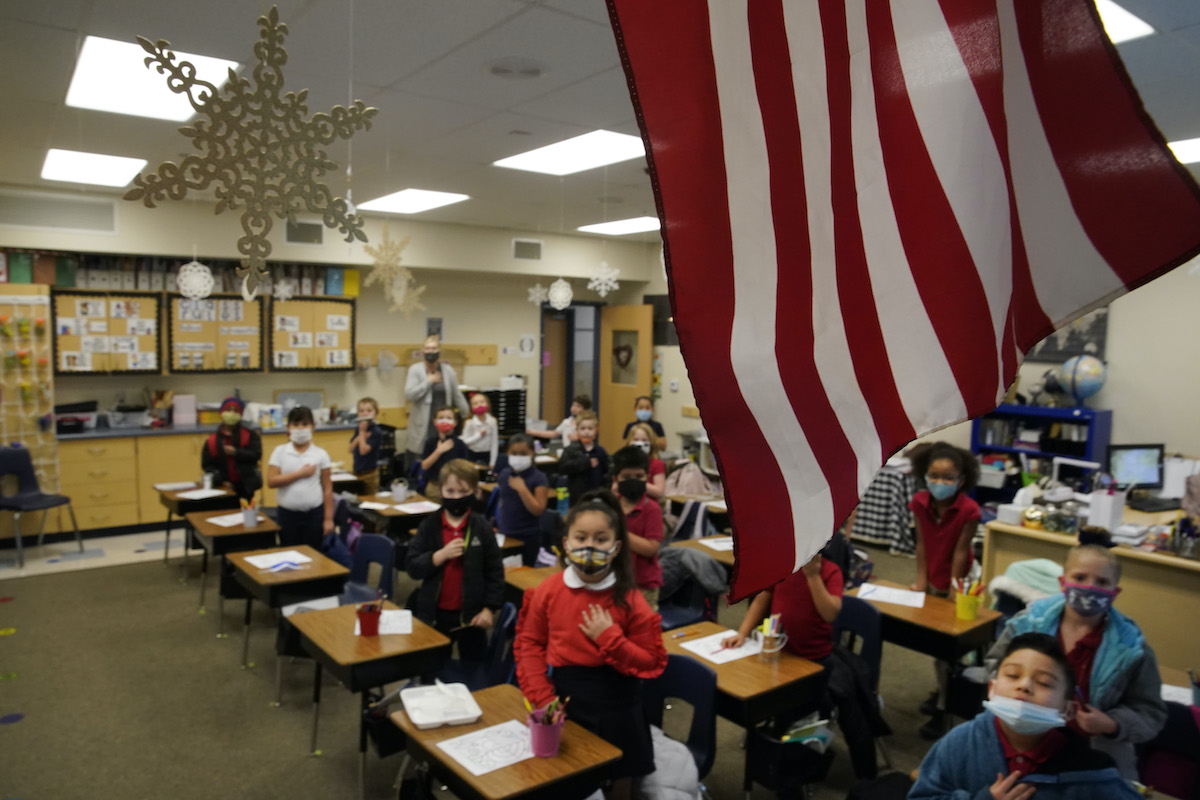 Young students recite the Pledge of Allegiance in a classroom