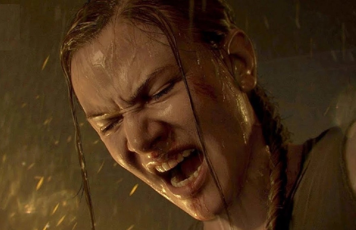 Close up of Abby's face in the last of us, part 2. Her mouth is open and her eyes squeezed shut as she screams in rage. It's raining and she's wet. Her blonde braid is hanging over one shoulder.