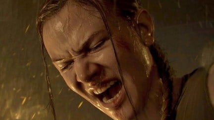 Close up of Abby's face in the last of us, part 2. Her mouth is open and her eyes squeezed shut as she screams in rage. It's raining and she's wet. Her blonde braid is hanging over one shoulder.