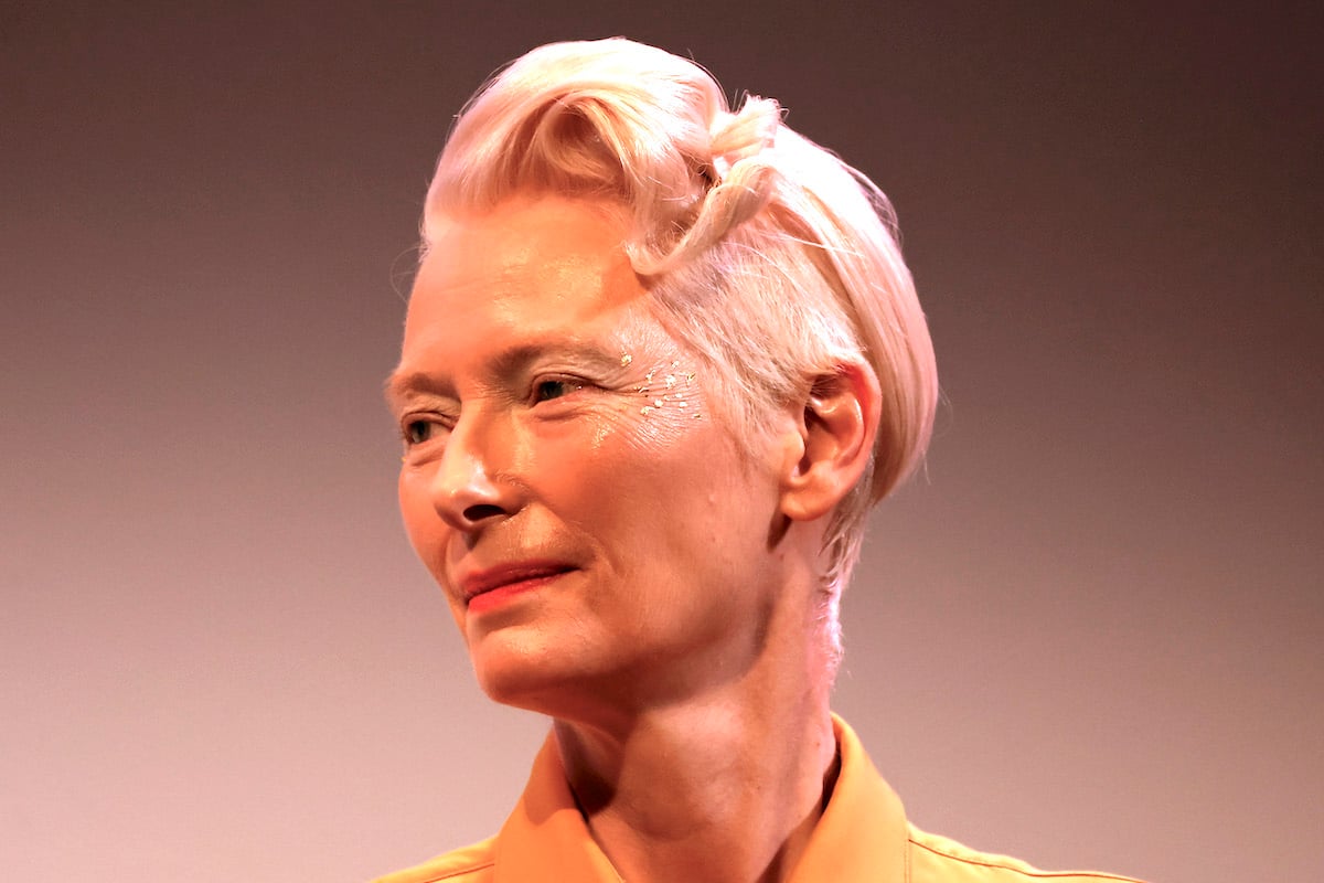 Tilda Swinton in close-up, looking to the side, with glitter on her face.