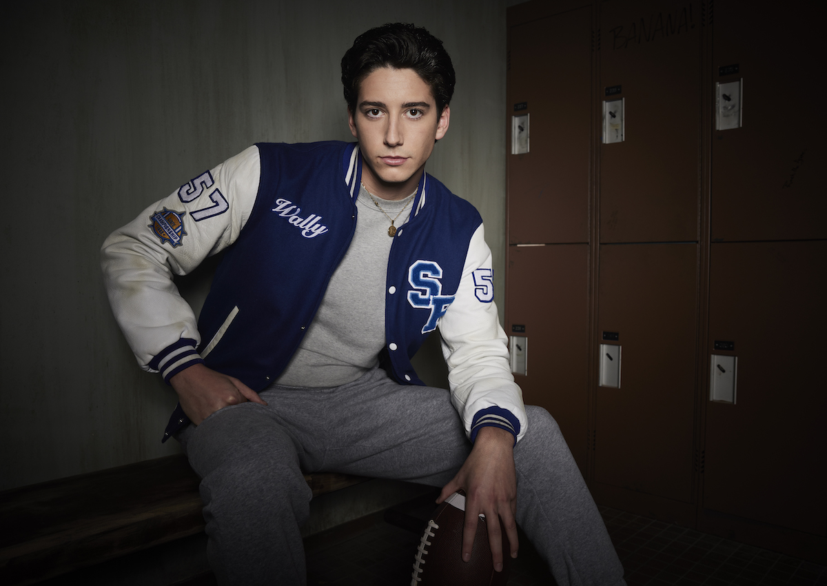 Milo Manheim as Wally in School Spirits, posing in front of a wall of lockers.